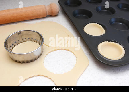 Auskleidung der Bun-Dose mit Kreisen von Gebäck zu Mince Pies, mit einem Nudelholz auf der Arbeitsplatte ausgerollt Stockfoto