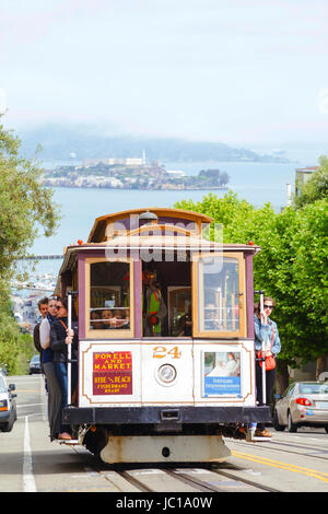 SAN FRANCISCO - 24 APRIL: Berühmte Seilbahn mit Menschen auf einer steilen Straße am 24. April 2014 in San Francisco, Kalifornien. Die Seilbahn ist Teil der intermodalen städtischen Verkehrsnetzes durch die San Francisco Municipal Railway betrieben. Stockfoto