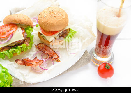 Zwei hausgemachte Burger serviert mit Glas Soda auf weißen Tisch Stockfoto