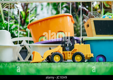 Tracktor Spielzeugauto mit Spielzeugkisten im Garten. Stockfoto