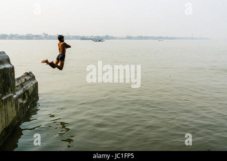 Ein Junge ist das Springen in der Hoogli Fluss von einer Wand Stockfoto