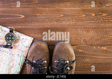 Wanderschuhe mit Topo Karte und Kompass auf Holz Hintergrund. Stockfoto