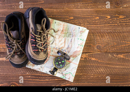 Wanderschuhe mit Topo Karte und Kompass auf Holz Hintergrund. Stockfoto