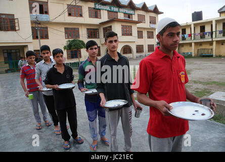 Srinagar, Kaschmir. 13. Juni 2017. Muslimischen Kaschmir Waisen Warteschlange für Iftar, Abendessen, wenn Muslime ihr Fasten während des Fastenmonats Ramadan in einem Waisenhaus "Jammu und Kaschmir Yateem Khana" in Srinagar, der Sommerhauptstadt von Kaschmir, 13. Juni 2017 zu brechen. Bildnachweis: Javed Dar/Xinhua/Alamy Live-Nachrichten Stockfoto