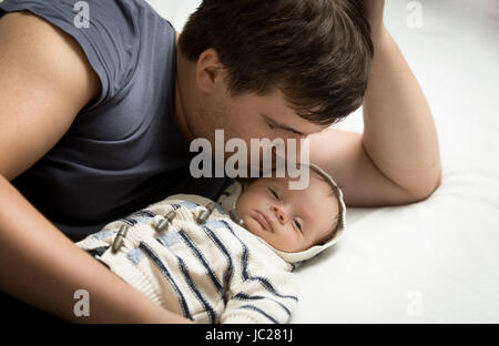 Porträt der schönen Papa küssen Baby Boy auf Bett liegend Stockfoto