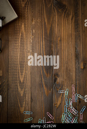 Vertikalen hölzernen Hintergrund mit Notebook und bunte Büroklammern. Platz für text Stockfoto