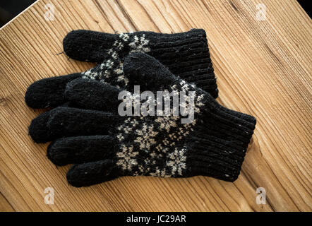 Nahaufnahme Foto Schwarz gestrickte Handschuhe liegen auf Holztisch Stockfoto