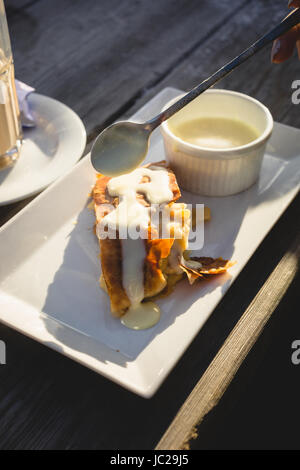 Nahaufnahme Foto Apfelstrudel mit Vanillesauce auf Holztisch Stockfoto