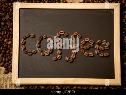 Nahaufnahme Foto des Wortes "Kaffee" geschrieben von Kaffeebohnen auf schwarze Kreide an Bord Stockfoto