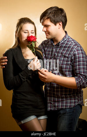 Schöne junge Frau riechen rote Rose präsentiert von junger Mann Stockfoto