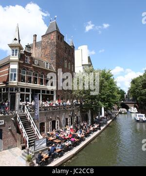 Touristen auf der Sommerterrasse entlang Oudegracht Kanal in der Innenstadt von Utrecht, Niederlande mit mittelalterlichen "Stadskasteel Oudaen". (Stich von 2 Bildern.) Stockfoto