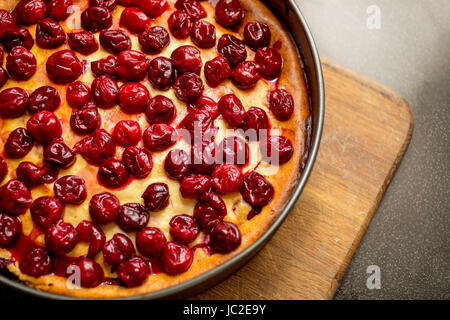 Closeup Schuss frisch gebackenem Kuchen verziert mit Kirschen auf Holzbrett Stockfoto