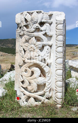 ein Stück der klassischen Altgriechisch geschnitzt Relief-Muster, Steinen und weißem Marmor auf einem Hintergrund von grünem Rasen, blühende rote Mohnblumen, blauer Himmel Stockfoto