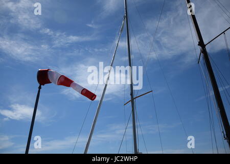 Windsack und Yacht Masten gegen blauen Himmel mit weißen Wolken Stockfoto