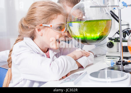 Lehrer und Schüler Chemiker betrachten Kolben mit Reagenzien im Labor lächelnd Stockfoto