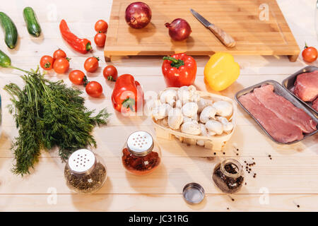 Nahaufnahme von frischem Gemüse und rohem Fleisch auf Holztisch Stockfoto