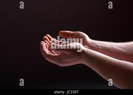 Offenen Handflächen Hände - Geste der männlichen Händen auf einem dunklen Hintergrund Stockfoto