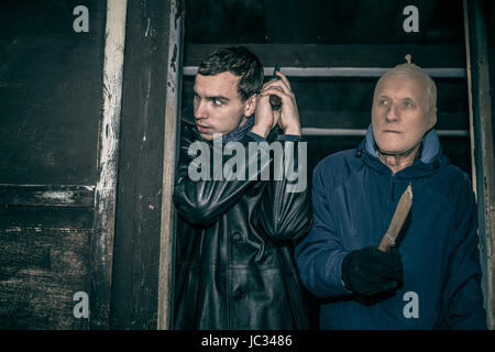 Zwei gefährliche bewaffnete Männer in alte dunkle Hütte versteckt. Stockfoto