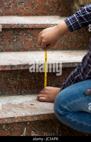 Closeup Aufnahme von Arbeitskraft Messung Höhe von Steintreppen Stockfoto