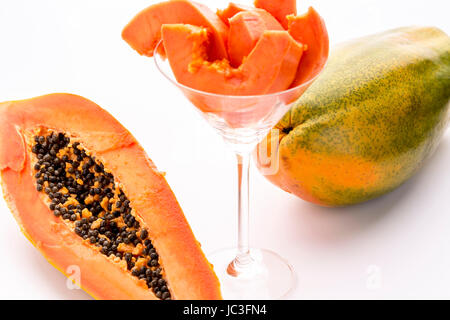 Eine ganze Reife Papaya und eine Hälfte dieser tropischen Frucht. Das saftige Fruchtfleisch umgibt eine innere Hohlraum, gefüllt mit zahlreichen schwarzen Samen. Stockfoto