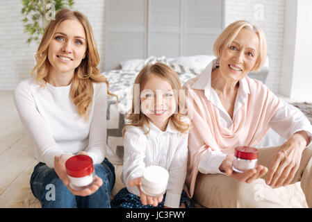 Mädchen, Mutter und Großmutter hält Gläser Creme Stockfoto