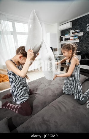 Zwei junge Schwestern Kissen kämpfen auf couch Stockfoto