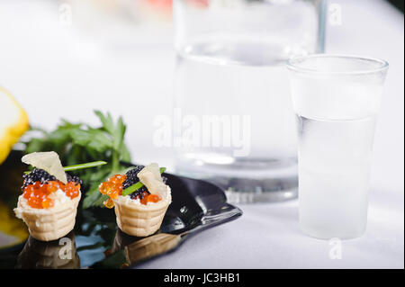 Snacks mit Lachsrogen und Gemüse auf einer schwarzen Platte Stockfoto