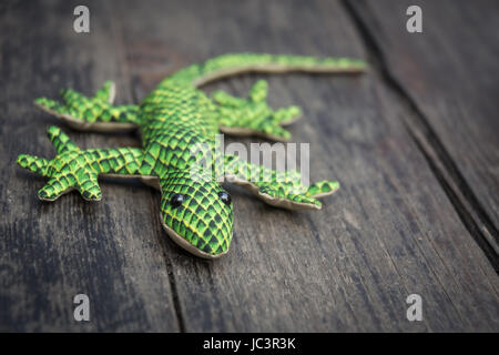 Nahaufnahme von einem Plüsch Gecko auf einem alten Holztisch Stockfoto