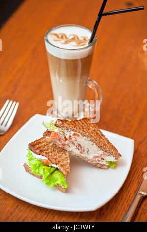 Sandwich mit Käse und Lachs und Gemüse mit latte Stockfoto