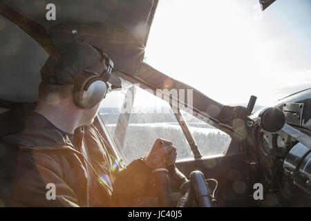 Ein Buschpilot schaut aus seinem Fenster während des Fluges durch die Wildnis Alaskas. Stockfoto