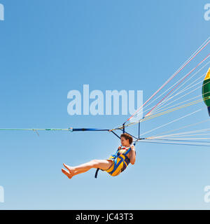 Mädchen am Fallschirm in blauen Himmel im Sommertag parasailing Stockfoto