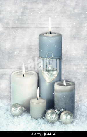 Vier blauen, grauen und weißen brennenden Advent Kerzen mit Schnee im shabby chic Stil. Stockfoto
