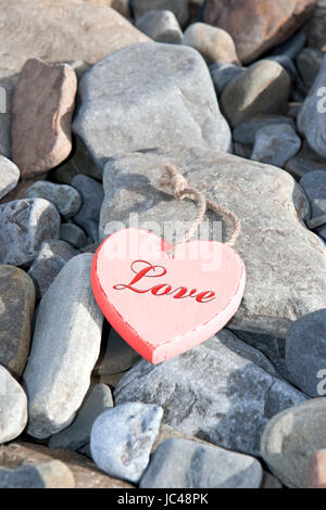 einzelne rote Holz Liebe Herz auf einem Kiesstrand in Irland Stockfoto