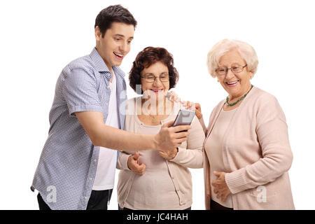 Junger Mann zeigen etwas auf einem Telefon mit zwei älteren Frauen isoliert auf weißem Hintergrund Stockfoto