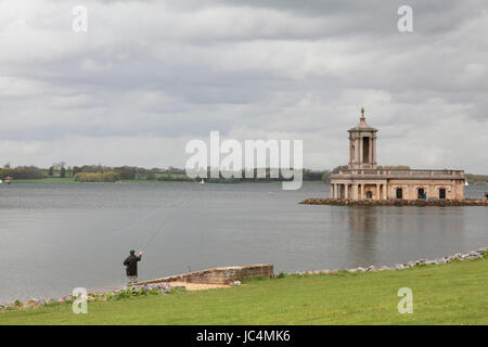 Ein Mann Fliegenfischen am Ufer des Rutland Water neben Normanton Kirche Stockfoto