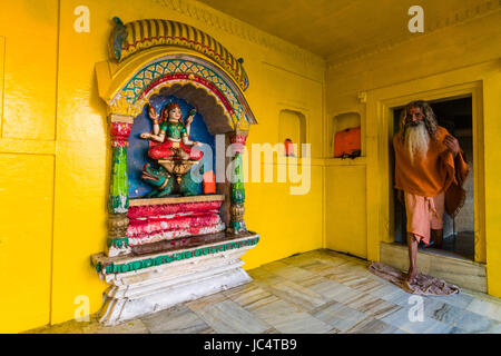 Ein sadhu, heiliger Mann, ein kleiner Tempel der Göttin Ganga am heiligen Fluss Ganges lalita Ghat gewidmet in der Vorstadt godowlia Stockfoto