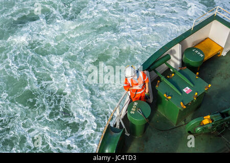 Weiblichen Crew-Mitglied mit Radio / Walkie-talkie in orange insgesamt und tragen Schutzhelm arbeiten an Deck von Autotransporter / Cargo Schiff auf hoher See Stockfoto
