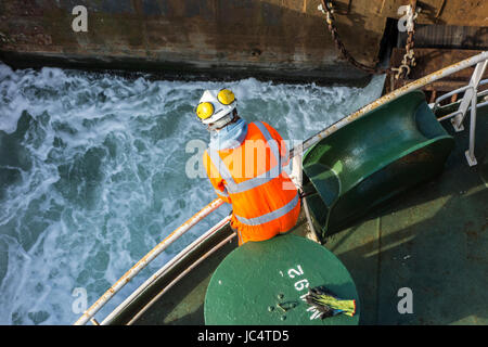 Weibliches Besatzungsmitglied in Orange insgesamt und tragen Schutzhelm arbeiten an Deck von Autotransporter / Frachter im Hafen Stockfoto