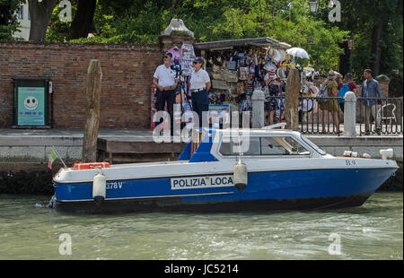 Venedig, Italien - 13. Juni 2017: Zwei Polizisten eine Radarfalle neben einem geschäftigen Stall mit touristischen Souvenirs am Canal Grande in Venedig tätig. Stockfoto