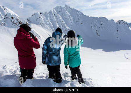 Profi-Snowboarder, Helen Schettini, Robin Van Gyn und Jamie Anderson, Blick auf Linien, die sie vorbereiten, auf einem Snowboard Trip nach Haines, Alaska zu fahren. Stockfoto