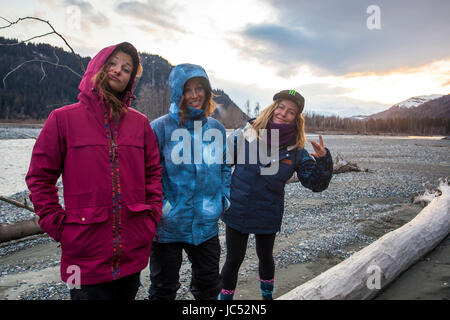 Professionelle Snowboarder Jamie Anderson, Robin Van Gyn und Helen Schettini hängen an der Seite eines Flusses nach einem Tag voller Snowboarden in Haines, Alaska. Stockfoto