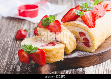 Hausgemachte Erdbeer-Kuchen mit Frischkäse, geschlagene Sahne, perfekte Sommer Saison Dessert serviert, auf rustikalem Holzbrett Rollen Stockfoto