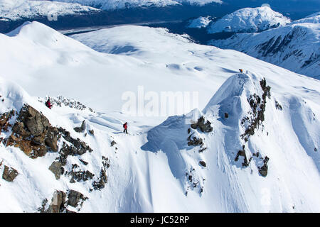 Professionelle Snowboarder Marie France Roy, Robin Van Gyn und Helen Schettini, stehen auf einem Berg und bereiten Sie sich auf ihren Snowboards Rückgang nach abgesetzt von einem Hubschrauber an einem sonnigen Tag in Haines, Alaska. Stockfoto