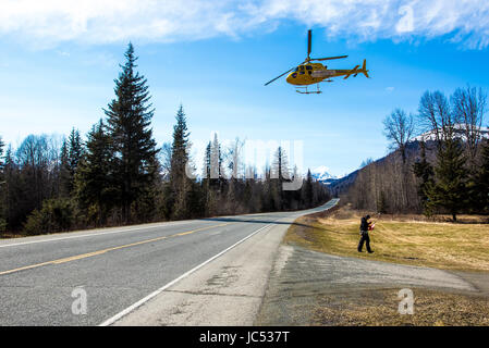 Ein Hubschrauber benutzt, um Skifahrer und Snowboarder auf der Spitze der Berge tragen startet vom Heliport in den Schnee an einem Frühlingstag in Haines, Alaska fliegen. Stockfoto