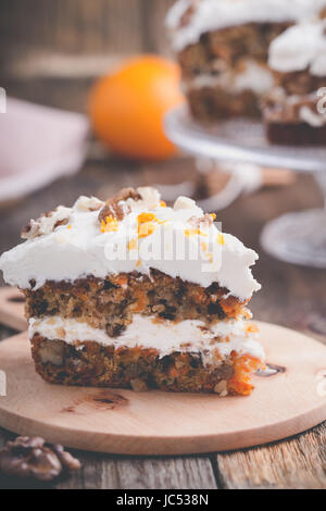 Karotte-Kuchen mit Walnüssen, Zimt und Orange Frischkäse Zuckerguss auf rustikalen Holztisch Stockfoto