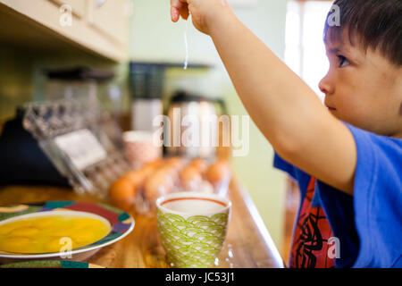 Vier Jahre alten japanischen American Boy hilft Koch von Eiern zu knacken. Stockfoto