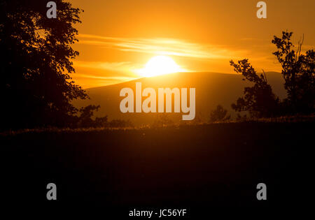 Die untergehende Sonne hinter den Hügeln der Südsteiermark Stockfoto