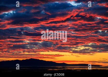 Das Abendrot des Sonnenuntergangs leuchtet auf der Unterseite der Wolken über Antelope Island.  Antelope Island ist die größte Insel im Great Salt Lake. Stockfoto