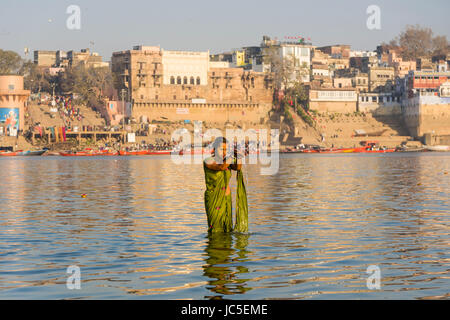 Eine Frau, Pilger, Badewanne und betend auf die sandbänke am heiligen Fluss Ganges, Panorama der Dashashwamedh Ghat, Main Ghat, in der Ferne Stockfoto