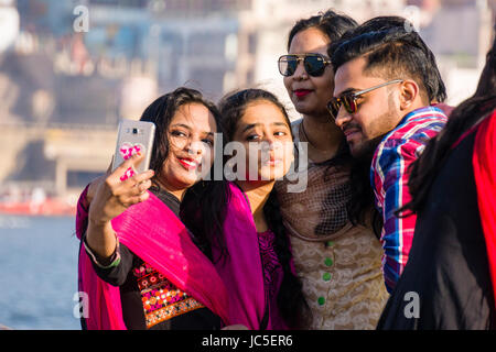 Junge moderne Männer und Frauen nehmen selfies auf die sandbänke am heiligen Fluss Ganges, Panorama der Dashashwamedh Ghat, Main Ghat, in der Ferne Stockfoto